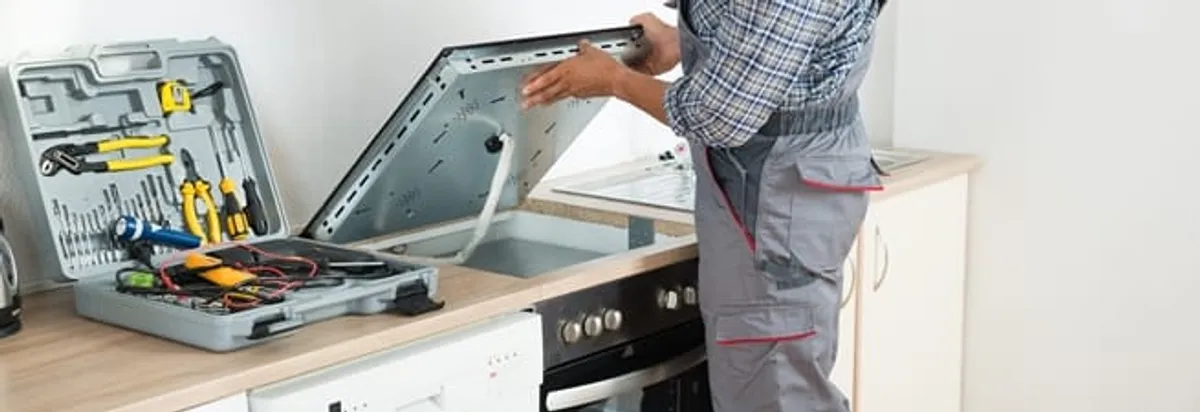 Cooktop repair technician lifting a built-in stovetop for service in Cape Coral, FL