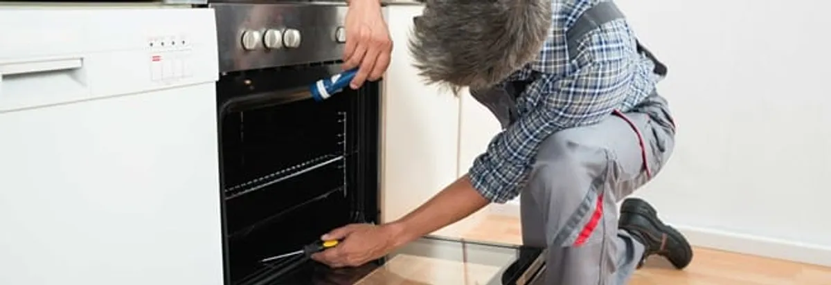 Oven repair technician inspecting and servicing an electric oven in Cape Coral, FL