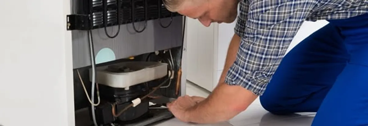 Refrigerator repair technician servicing the compressor and condenser area in Cape Coral, FL