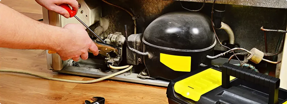 Refrigerator repair technician fixing the compressor and wiring in Cape Coral, FL